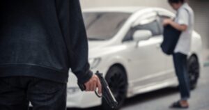 A man with a gun approaching a woman getting into her white car
