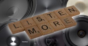 'listen more' spelled out in scrabble tiles with speakers behind them